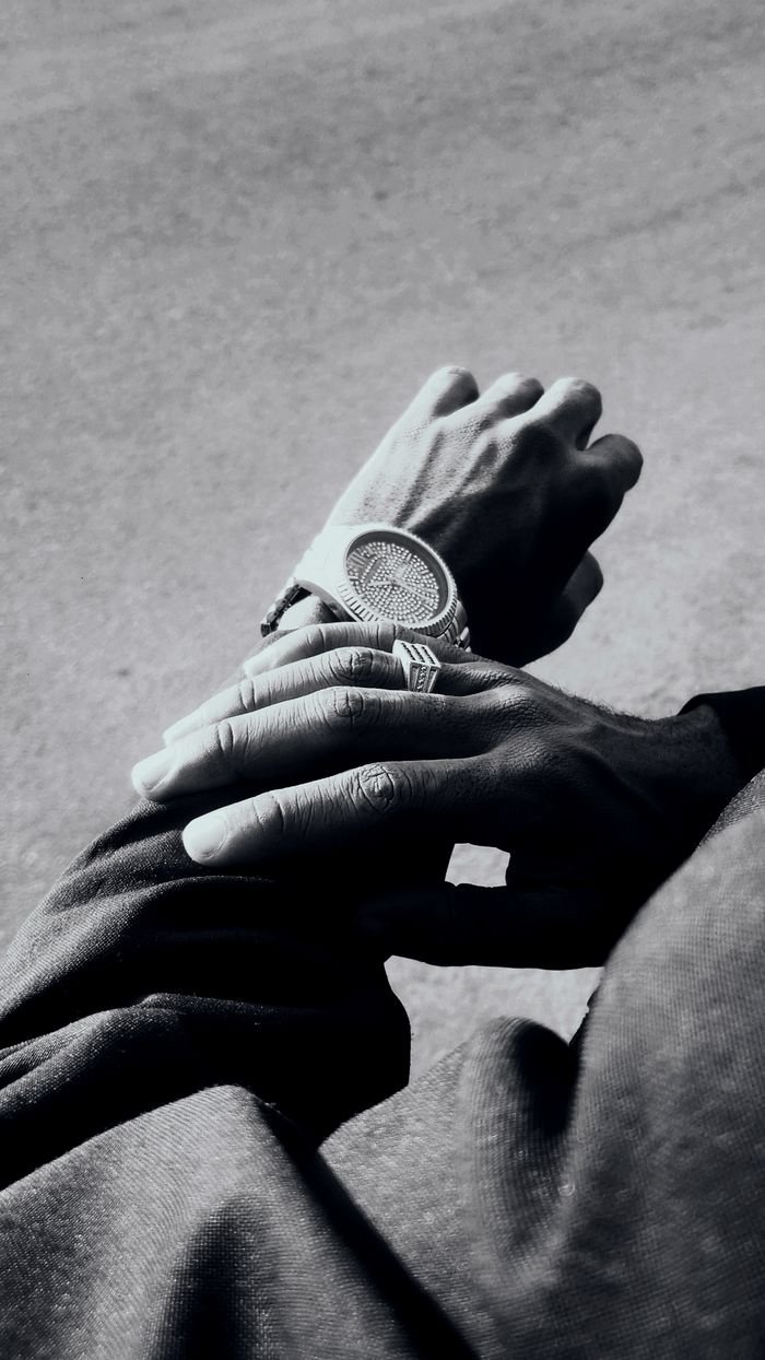 Black and white photo of hands wearing a stylish watch, casting a shadow.